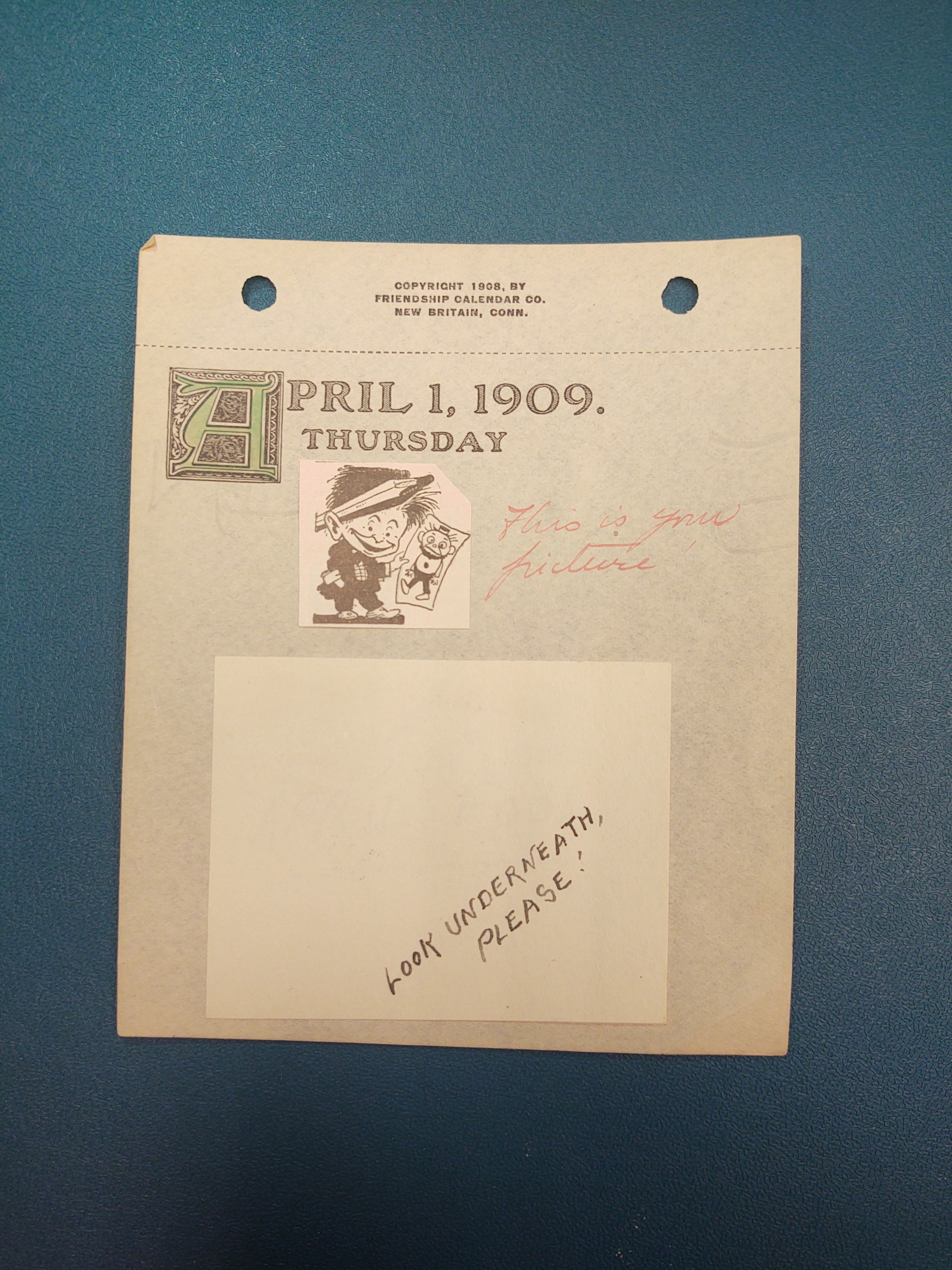 April 1, 1909. Thursday: A short man with a big a pencil behind his ear is shown holding up a piece of paper with a drawing on it. The drawing on the paper is of another goofy looking man. The image appears to be cut out (probably from a magazine) and pasted onto the page.